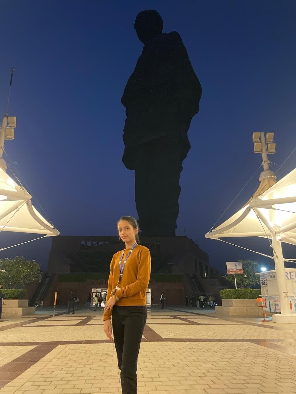 Siddhiksha Patel standing at night before a monumental statue.