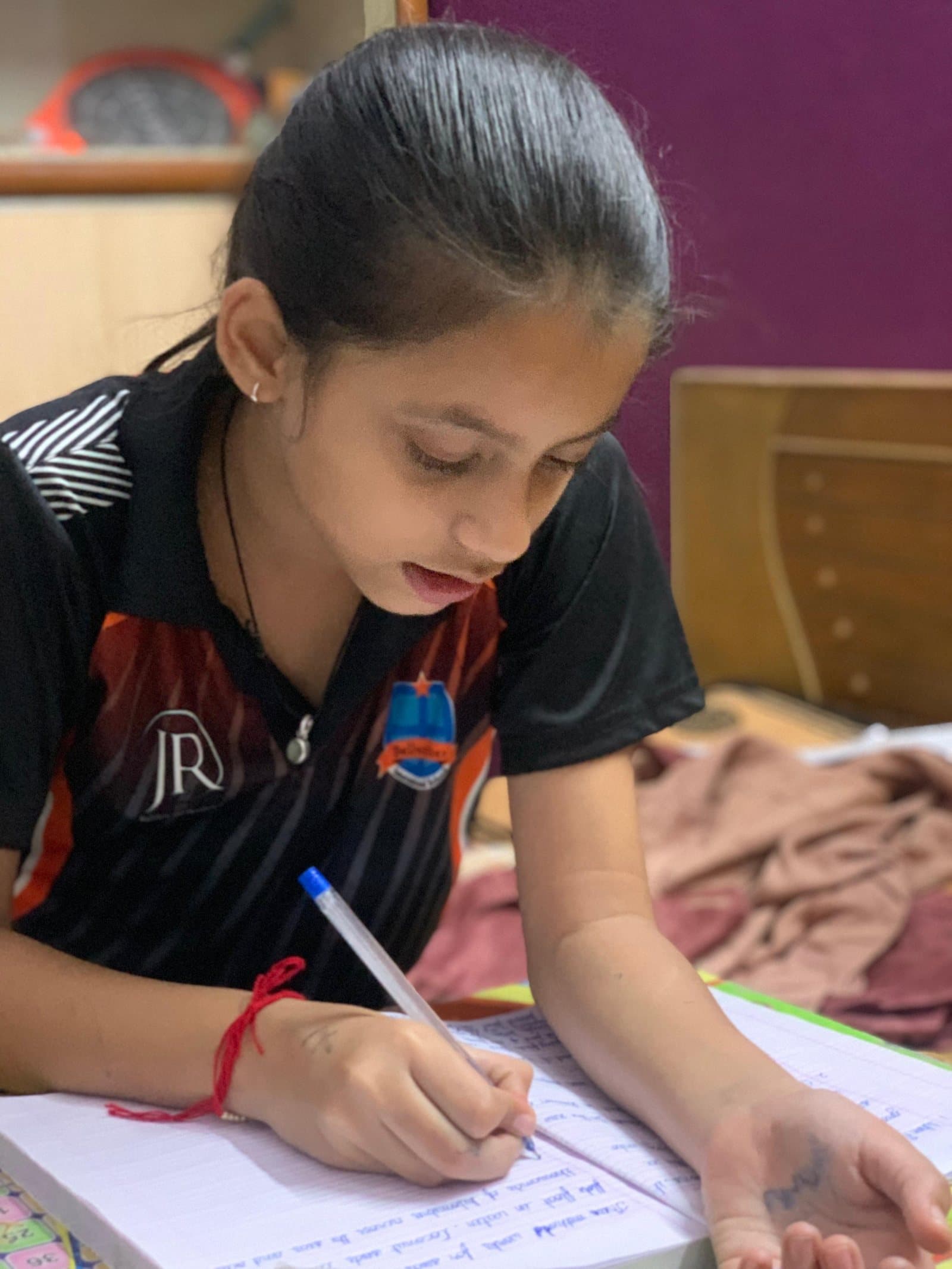 Siddhiksha Patel writing in a notebook.